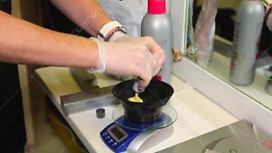 Stylist hairdresser makes hair coloring, blonding, coloring hair roots. She uses the brush. Close view. Hairdresser`s hands in bla