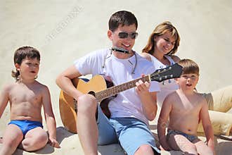 Guy plays guitar and lip accordion with children
