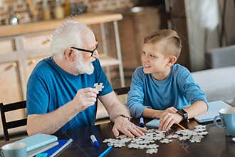 Joyful nice man collecting jigsaw puzzles