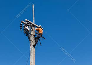 Electricians climbing work in the height on concrete electric power pole