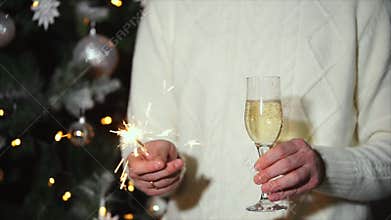 Man is holding sparkler and glass of champagne in party of New year celebration