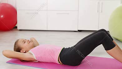 Young girl exercising at home - doing abs