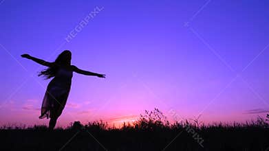 Silhouette of young girl dancing at pink sunset