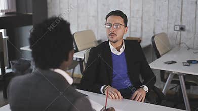 Two men sit at the office, talking and negotiate