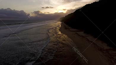 Aerial drone footage of ocean waves breaking before the shore on sunset. Bali, Indonesia