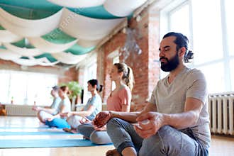 Man with group of people meditating at yoga studio