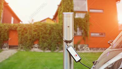 Close up of charging station. A cable is connected to the station, which charges an electric car.