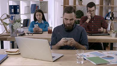 Casual businessman texting on smartphone in office