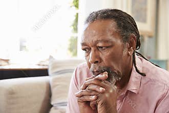 Senior Man Sitting On Sofa At Home Suffering From Depression