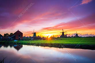 Traditional village with dutch windmills and river at sunset, Holland, Netherlands.