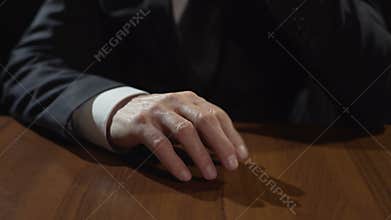 Frustrated mafia boss drumming fingers on table, thinking or making decision