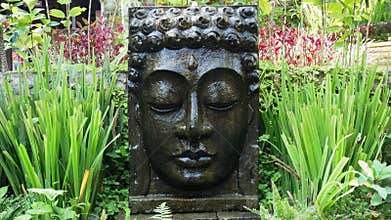Buddha with falling water in the tropical garden in Ubud, Bali.
