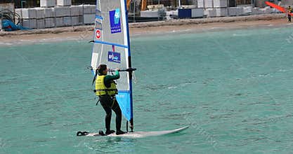 Young girl windsurfing in the blue sea