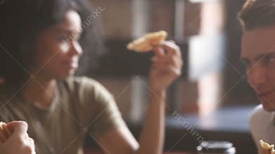 Multi-ethnic black and white friends eating pizza at meeting indoors