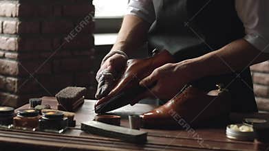 Shoe shop. Shoes master polishes boots