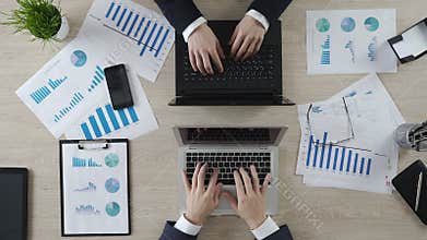 Hands of business partners typing on laptops opposite each other, negotiations