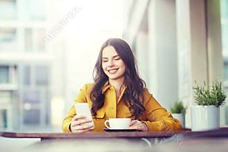 Happy woman texting on smartphone at city cafe