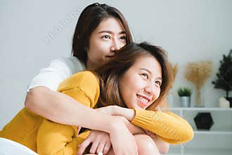 Beautiful young asian women LGBT lesbian happy couple sitting on bed hugging and smiling together in bedroom at home.