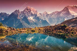 Mountains with snow covered peaks, red sky reflected in lake