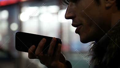 Young man sending voice message with cell phone