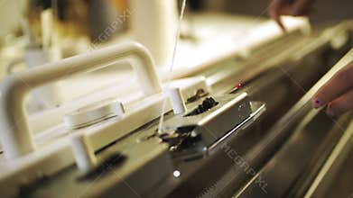 Woman knitter hand working on weaving machine. Knitting machine production