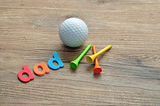 A golf ball with tee`s and the word dad