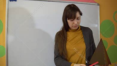 Female teacher stand near blackboard in elementary school teaching.