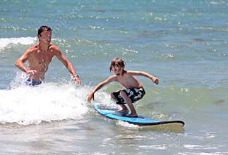 Father teaching his young son how to surf