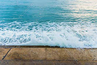 Sea water wave splashing on embankment, forming a spray.Exotic w