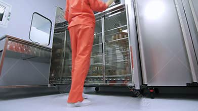 Factory worker in orange protective suit opening refrigerator storage