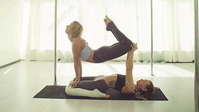 Two young women practicing acrobatic yoga.