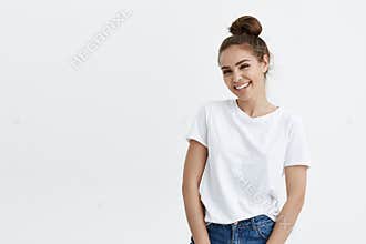 Portrait of elegant modern european woman with bun hairstyle smiling broadly at camera, expressing excitement while