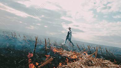 Postapocalypse. Girl on the scorched field. Around the fire and smoke