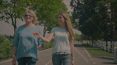 Chatting senior mother and adult daughter walking in park