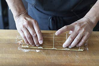 Sushi chef rolling up sushi in a mat