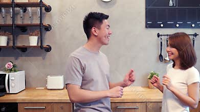 Beautiful happy asian couple are dancing in the kitchen at home. Young asian couple have romantic time listening music at home.