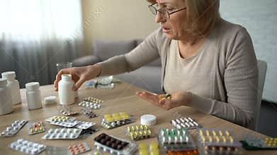 Senior woman taking capsules from all bottles, self-medication, pills addiction