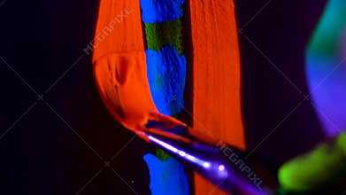 Close up The bodyart ultraviolet painter draws on the body of Beautiful young girl close up