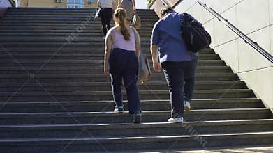 Fat couple walking together on stairs, problems of overweight among young people