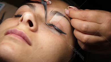 Beauty and fashion concept. Preparation for Eyelash Extension Procedure. Beautician prepares the eyelashes of a young