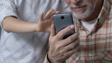 Grandson teaching granddad to use smartphone application, showing thumbs up