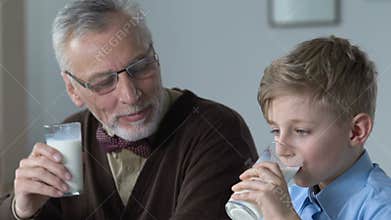 School boy and grandfather drinking milk together in morning, family breakfast