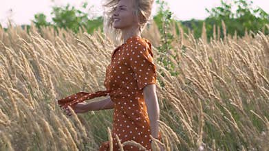 Attractive fun hippie blonde woman in the field at sunset having good time outdoors. Slow motion. Female spinning in the field
