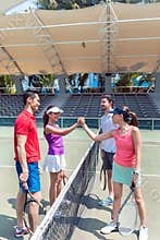 Four young tennis players putting hands together before a doubles match