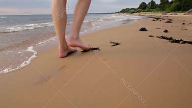 Woman walking on sand beach leaving footprints in the sand