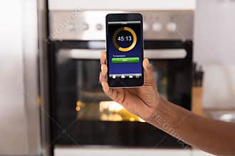 Woman Operating Oven Appliance With Mobile Phone App