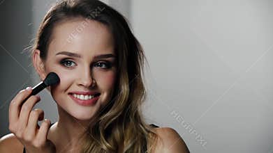 Woman with beauty face applying makeup blush with brush