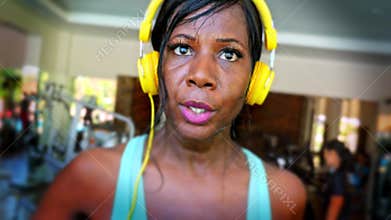 Frontal close up head shot of young attractive and fit black afro American woman running hard sprinting on treadmill workout