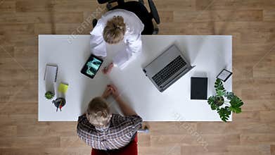 Young woman doctor is showing x-ray scan on tablet to patients and explaining disease, man at doctor, medical concept