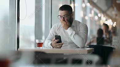 Bearded man with glasses saw the good news on the phone and was happy. Man Businessman happy talking on the phone.